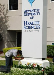 Ein Arbeiter montiert Schriftzug und Logo der neuen Universität