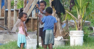 Kinder vor einem zerstörten Haus