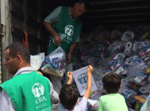 ADRA Mitarbeiter und Schulkinder verladen Wasserflaschen und Hygiene-Kits 