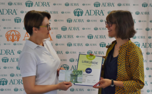 Stiftungsbotschafterin Michaela Sierra Lois (re.) überreicht Hanna Arhin-Sam von ADRA den symbolischen Spendenscheck.