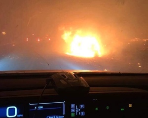 Sicht durch Windschutzscheibe eines Fahrzeugs, das Paradise verlässt, auf ein brennendes Auto