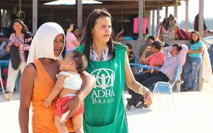 ADRA Mitarbeiterin betreut Mutter mit Kleinkind in Auffanglager