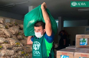 Mitarbeiter von ADRA Paraguay trägt Sack mit Hilfsgütern aus dem Lagerhaus