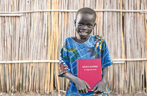 Ein afrikanisches Kind mit der Bibel in der Sprache seines Herzens.