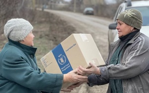 ADRA-Freiwillige übergibt WFP-Nahrungsmittelpaket an Bewohnerin einer Grenzregion in Luhansk.